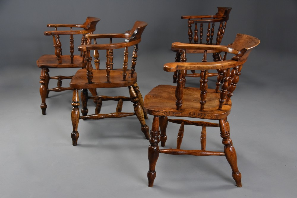 A set of four mid-19th-century Smokers Bow Windsor armchairs crafted from warm brown timber with turned spindles, sweeping armrests, and sculpted seats. View IX