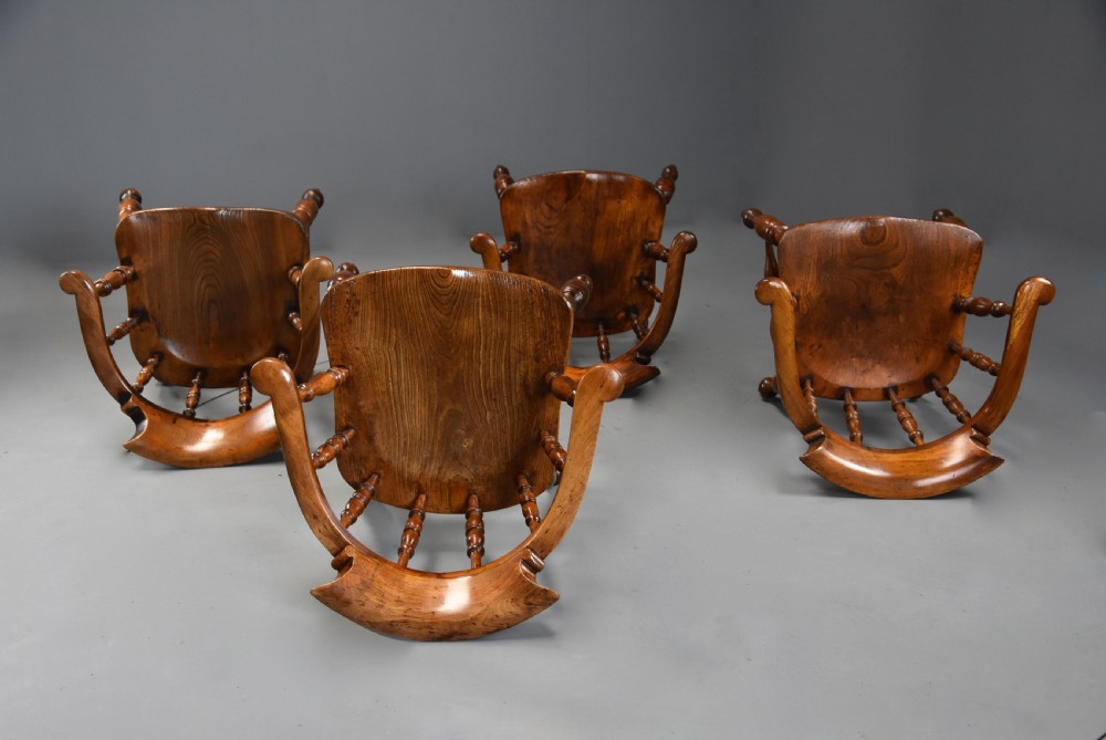 A set of four mid-19th-century Smokers Bow Windsor armchairs crafted from warm brown timber with turned spindles, sweeping armrests, and sculpted seats. View X