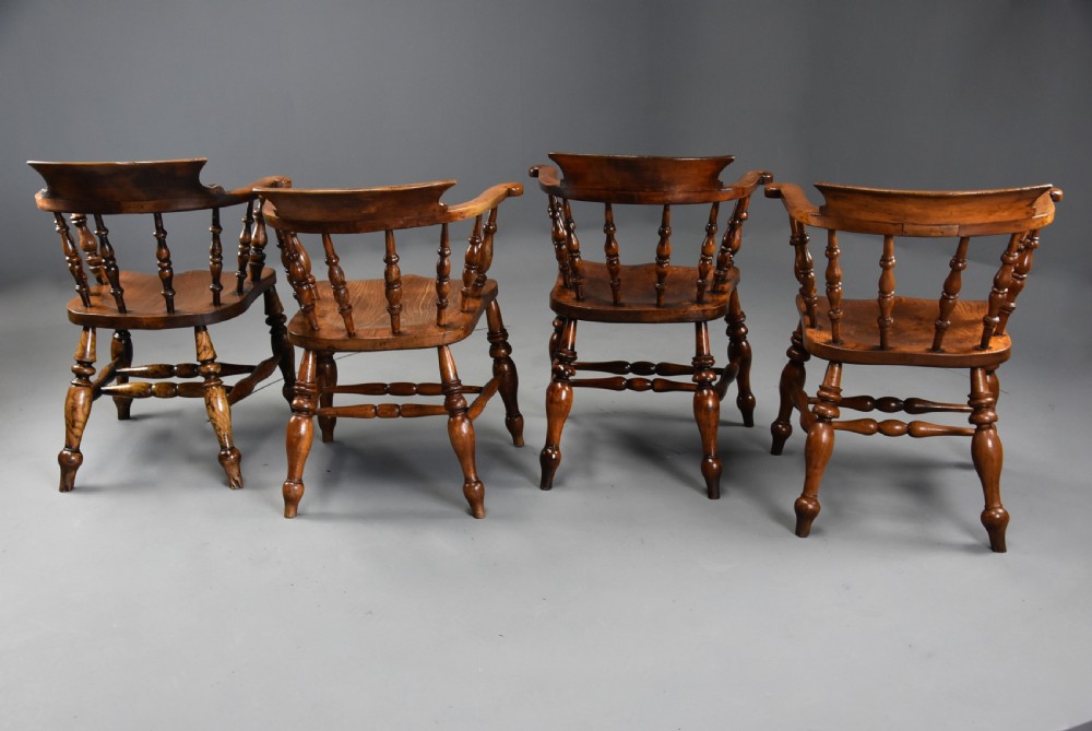 A set of four mid-19th-century Smokers Bow Windsor armchairs crafted from warm brown timber with turned spindles, sweeping armrests, and sculpted seats. View XII