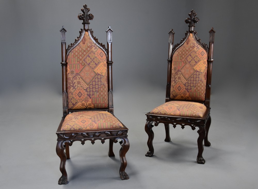 A pair of mid-19th century carved rosewood Gothic Revival hall chairs featuring pointed arch backs, decorative finials, patterned fabric upholstery, and cabriole legs. View II