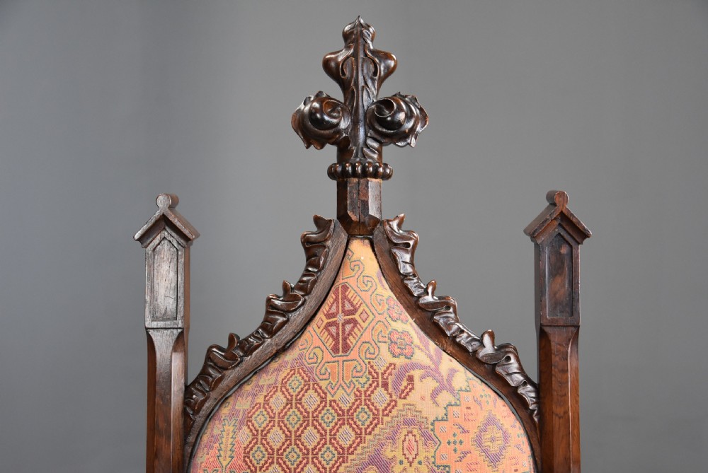 A pair of mid-19th century carved rosewood Gothic Revival hall chairs featuring pointed arch backs, decorative finials, patterned fabric upholstery, and cabriole legs. View VI