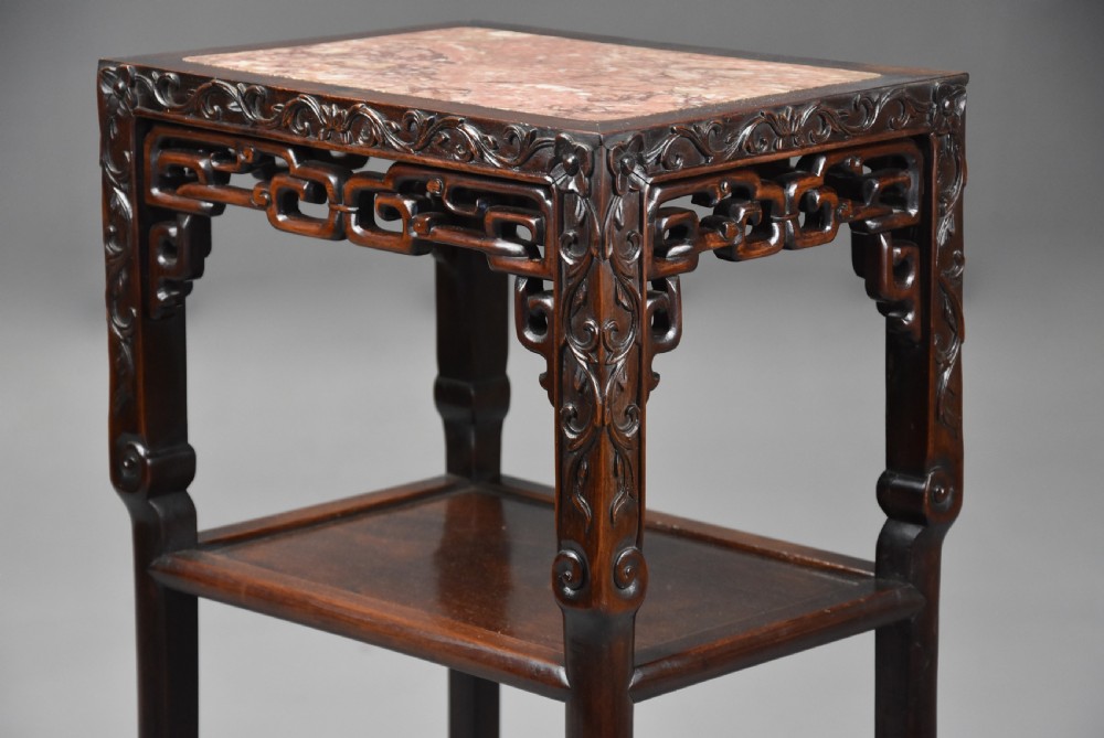 A late 19th-century rectangular Chinese dark hardwood pot stand featuring a pink marble insert top, pierced openwork aprons, and two lower tiers. View II