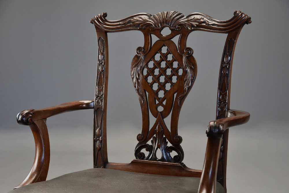 A pair of late nineteenth century mahogany open armchairs featuring carved pierced splat backs and dark green leather upholstered seats. View V
