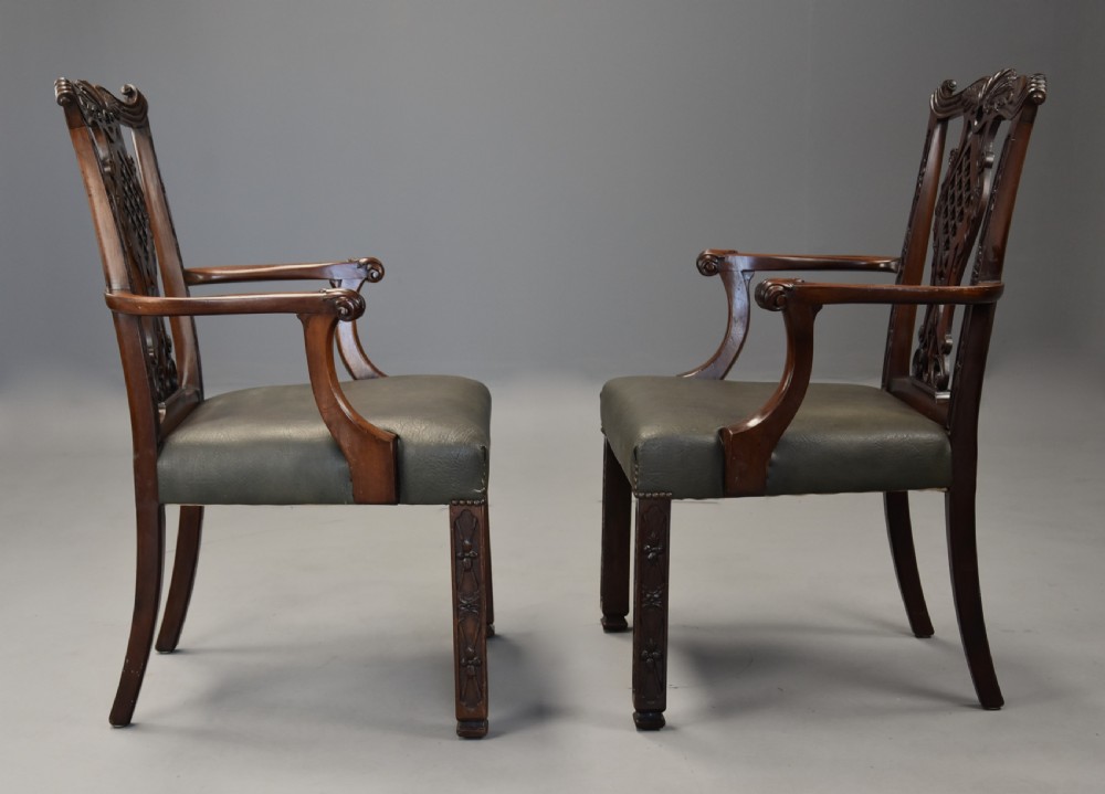 A pair of late nineteenth century mahogany open armchairs featuring carved pierced splat backs and dark green leather upholstered seats. View X
