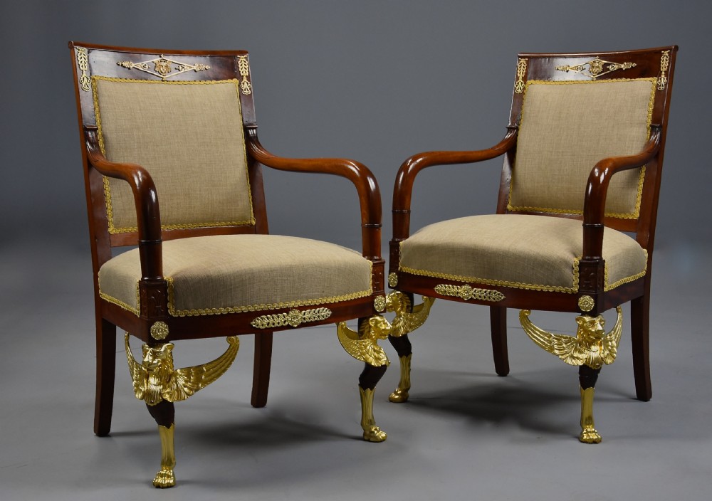 A pair of late 19th-century French mahogany open armchairs featuring gilt-bronze winged lion monopodia legs and beige fabric upholstery. View II