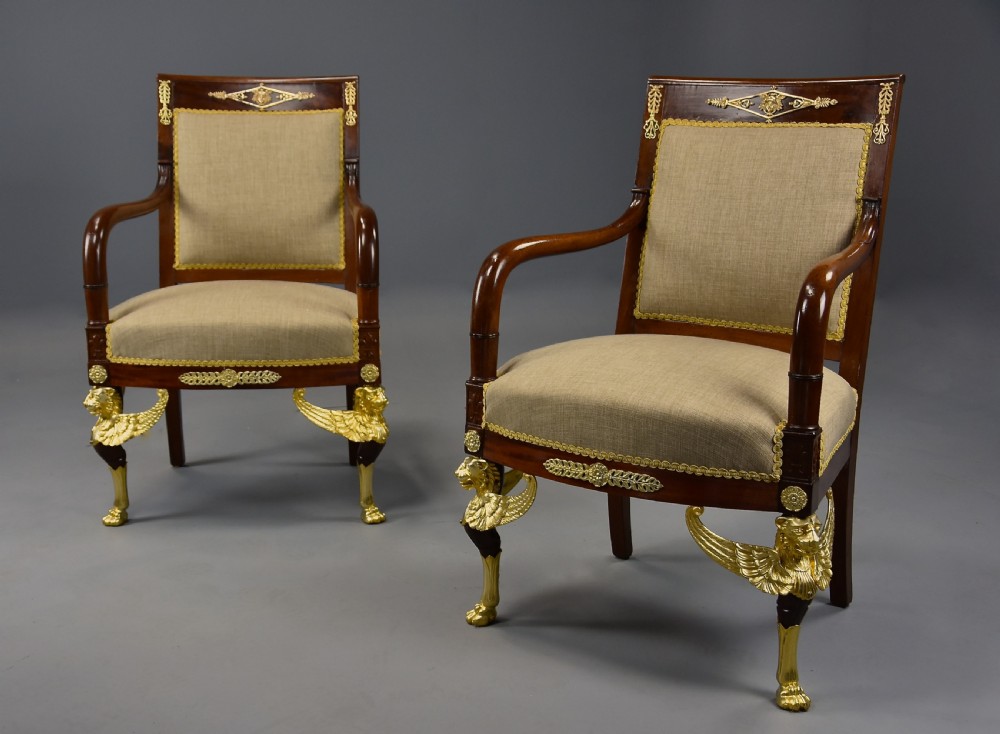A pair of late 19th-century French mahogany open armchairs featuring gilt-bronze winged lion monopodia legs and beige fabric upholstery. View VI