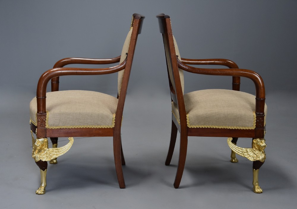 A pair of late 19th-century French mahogany open armchairs featuring gilt-bronze winged lion monopodia legs and beige fabric upholstery. View XIII