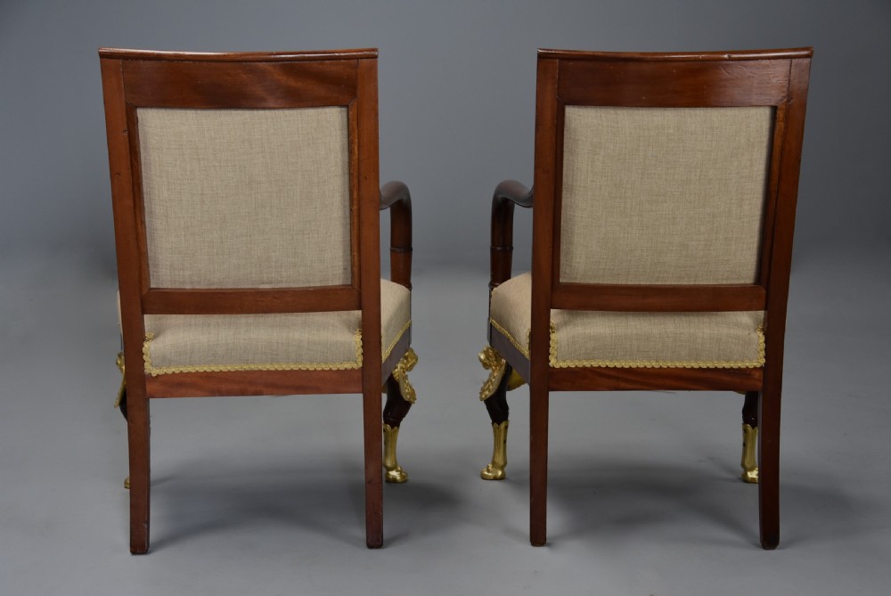 A pair of late 19th-century French mahogany open armchairs featuring gilt-bronze winged lion monopodia legs and beige fabric upholstery. View XV