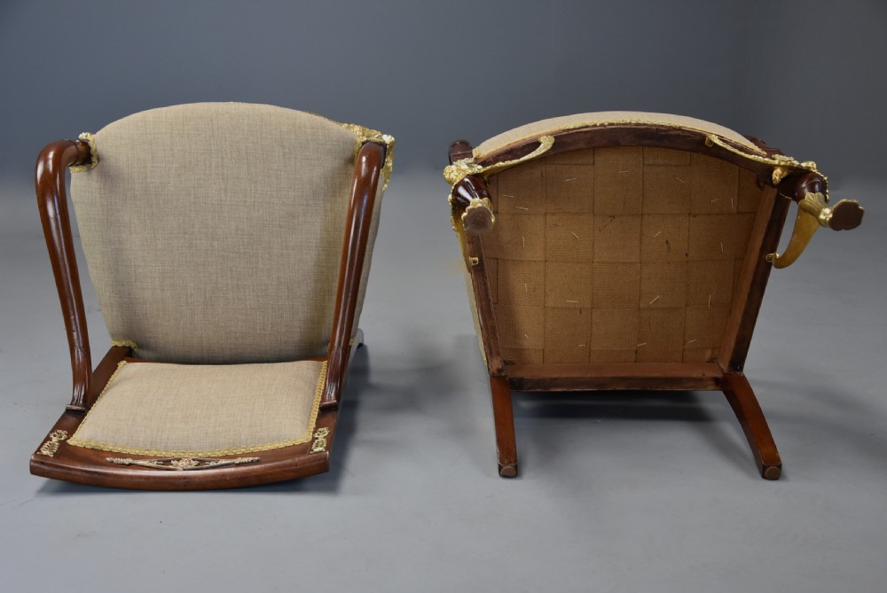 A pair of late 19th-century French mahogany open armchairs featuring gilt-bronze winged lion monopodia legs and beige fabric upholstery. View XVI
