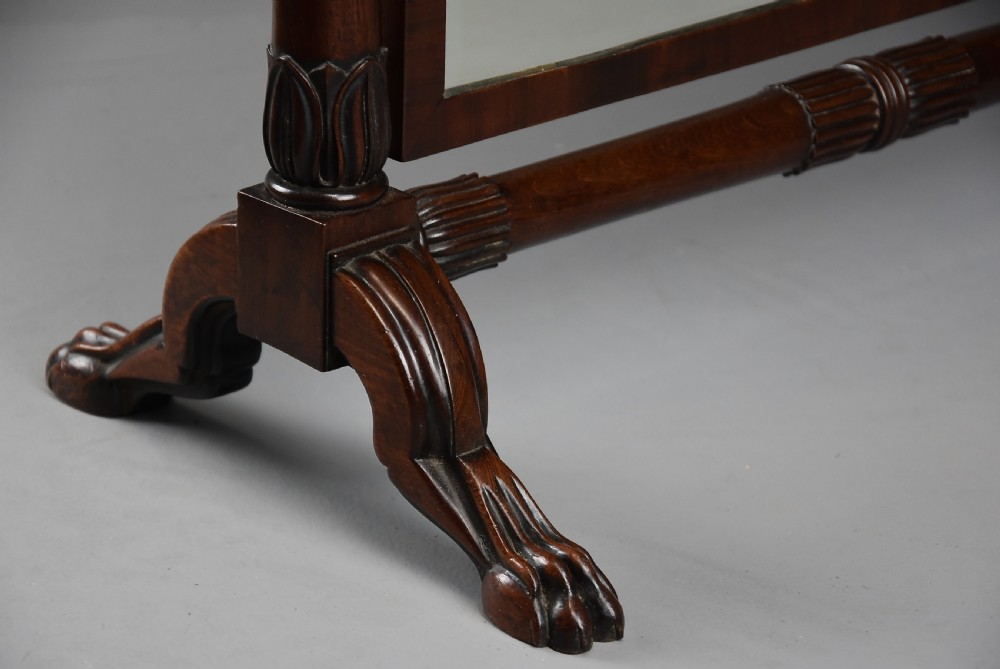A 19th-century Regency dark mahogany rectangular dressing mirror set between carved column supports on paw feet. View VIII
