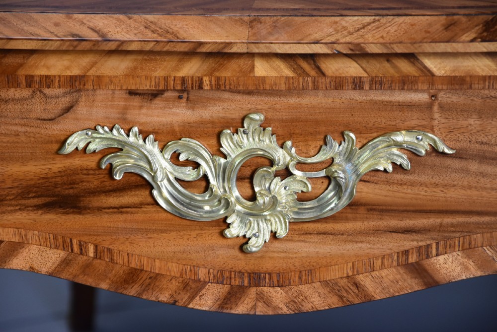 A mid-19th-century French style bureau plat desk crafted from goncalo alves wood featuring a black leather inset top, three frieze drawers, ornate gilt-bronze mounts, and cabriole legs. View VII