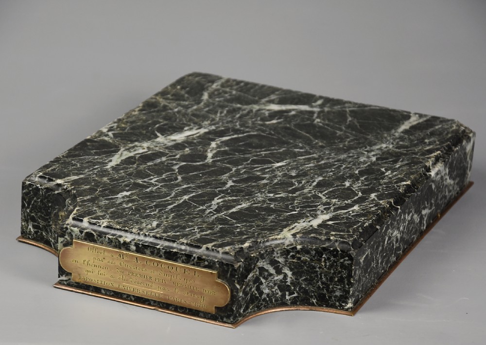 A dark brown patinated bronze sculpture of a standing male figure resting on a rectangular marble base with an etched metal title plaque. View XII
