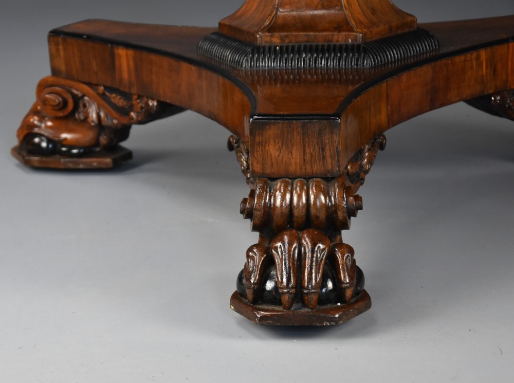 A 19th-century circular William IV rosewood tilt-top breakfast table featuring a central flared pedestal and a triform base on carved feet. View X
