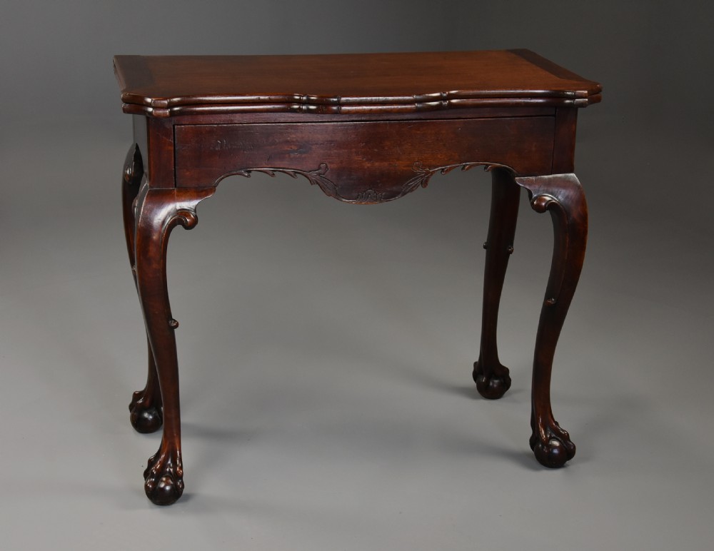 A dark walnut fold-over tea table featuring cabriole legs with carved knees ending in ball-and-claw feet and a decorative carved apron. View III