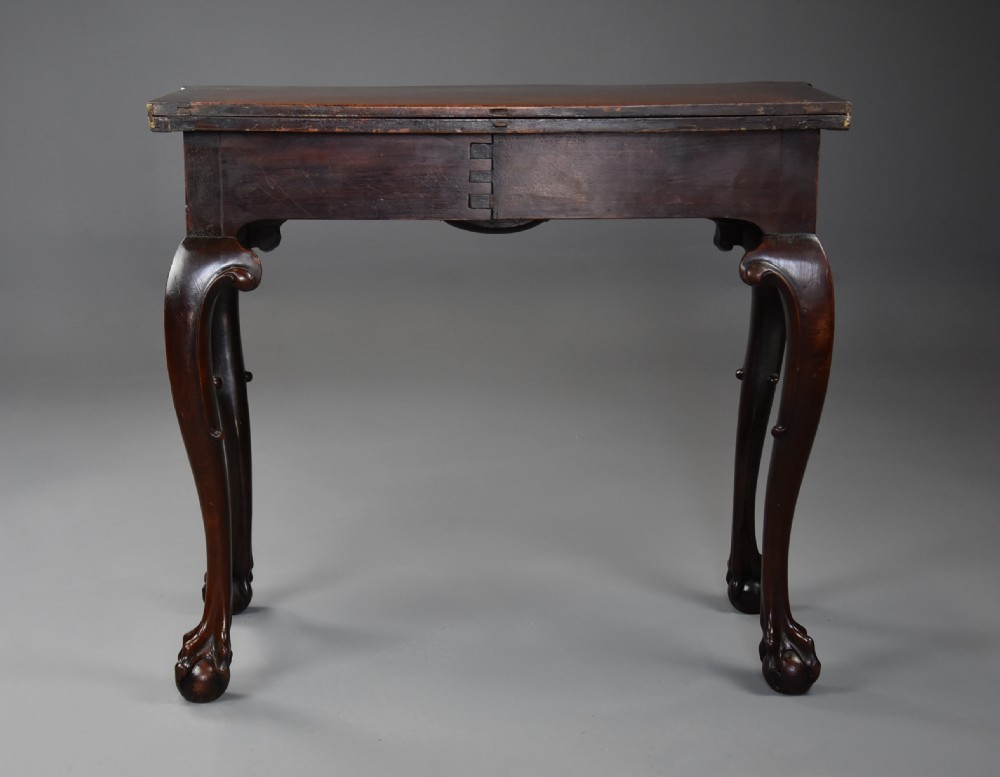 A dark walnut fold-over tea table featuring cabriole legs with carved knees ending in ball-and-claw feet and a decorative carved apron. View XVIII