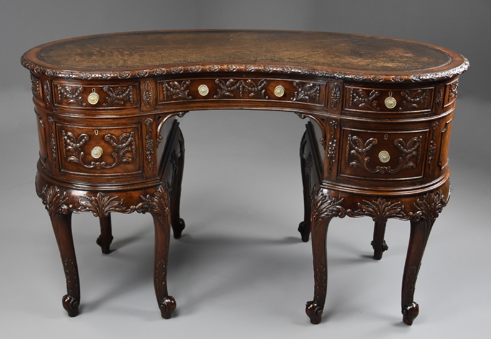 An Edwardian carved mahogany kidney-shaped desk featuring an inset leather writing top, ornate carved drawer fronts, and cabriole legs. View II