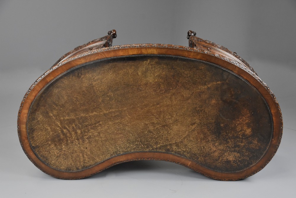 An Edwardian carved mahogany kidney-shaped desk featuring an inset leather writing top, ornate carved drawer fronts, and cabriole legs. View IX