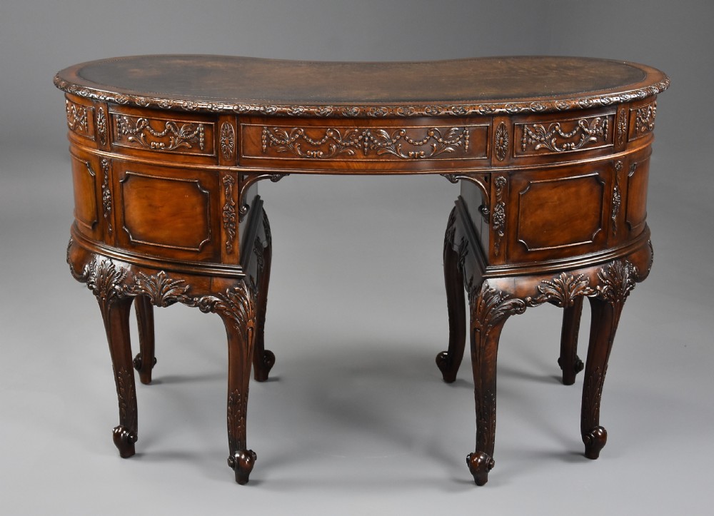 An Edwardian carved mahogany kidney-shaped desk featuring an inset leather writing top, ornate carved drawer fronts, and cabriole legs. View XI