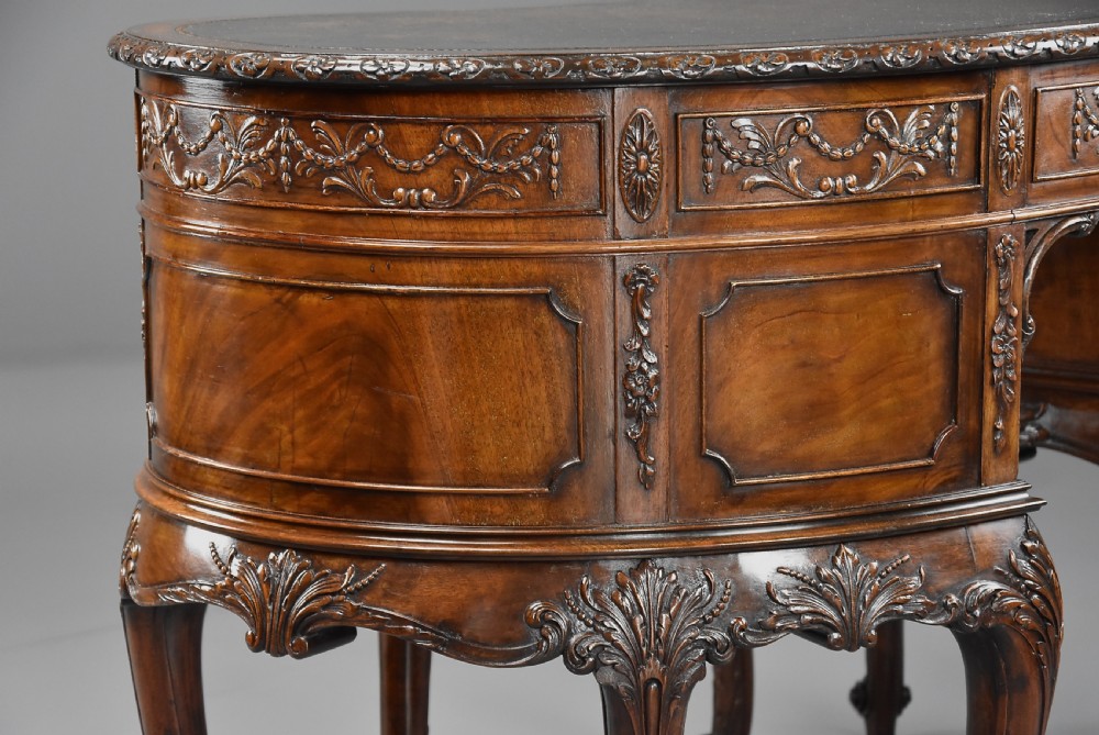 An Edwardian carved mahogany kidney-shaped desk featuring an inset leather writing top, ornate carved drawer fronts, and cabriole legs. View XIII
