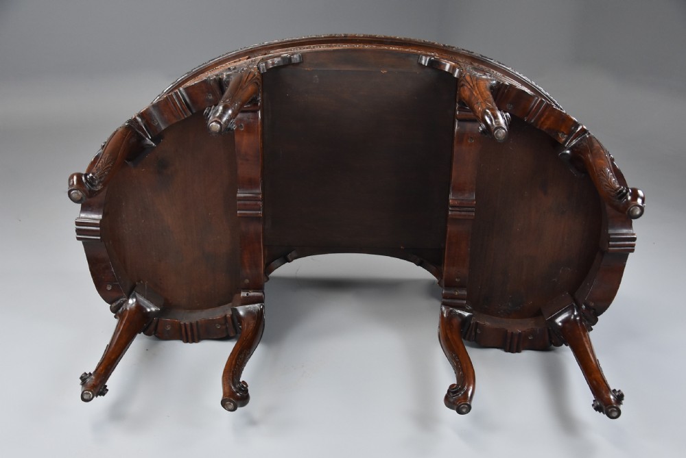 An Edwardian carved mahogany kidney-shaped desk featuring an inset leather writing top, ornate carved drawer fronts, and cabriole legs. View XV