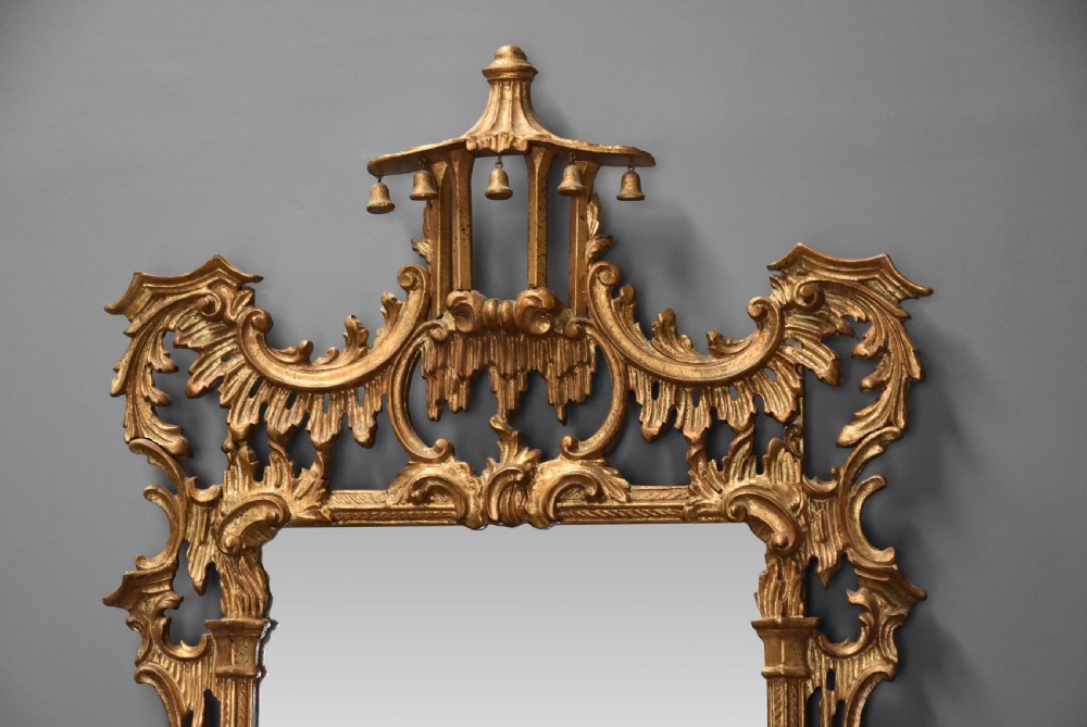 An intricately carved gold giltwood wall mirror featuring a pagoda cresting with hanging bells, acanthus leaf flourishes, and Rococo scrollwork framing a rectangular glass plate. View III