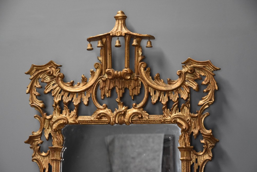 An intricately carved gold giltwood wall mirror featuring a pagoda cresting with hanging bells, acanthus leaf flourishes, and Rococo scrollwork framing a rectangular glass plate. View VIII