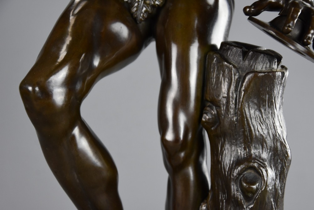 A late nineteenth-century dark brown patinated bronze sculpture depicting a nude dancing faun playing cymbals on a circular base. View XII