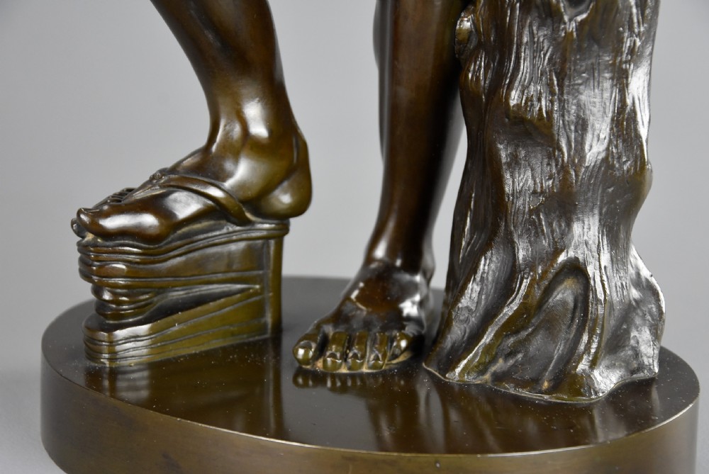 A late nineteenth-century dark brown patinated bronze sculpture depicting a nude dancing faun playing cymbals on a circular base. View XIII