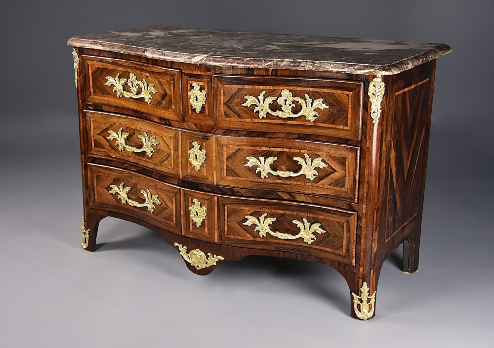 An 18th-century French Regence serpentine commode crafted in rosewood parquetry with gilded ormolu drawer pulls and a contoured marble top. View III