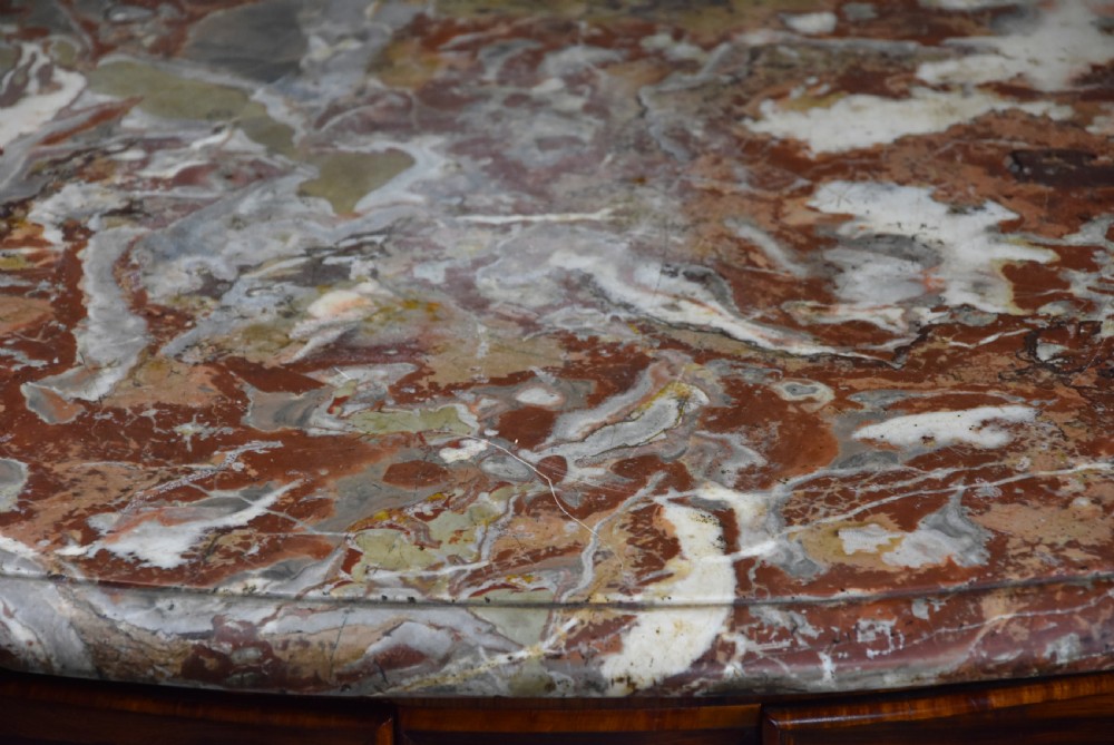 An 18th-century French Regence serpentine commode crafted in rosewood parquetry with gilded ormolu drawer pulls and a contoured marble top. View XIV