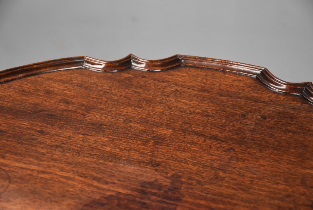 An 18th-century George II mahogany tilt-top tripod table featuring a carved piecrust rim, a turned column stem, and cabriole legs. View IX