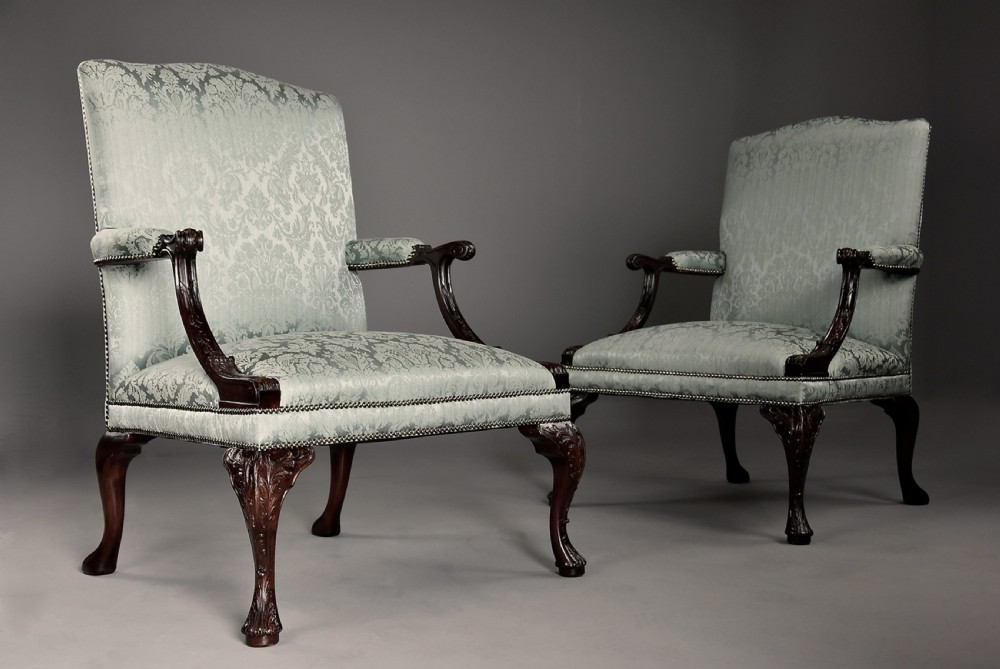 A pair of early 20th-century mahogany Gainsborough-style armchairs featuring carved cabriole legs with claw and ball feet, upholstered in light blue patterned damask fabric with brass stud trimming. View II