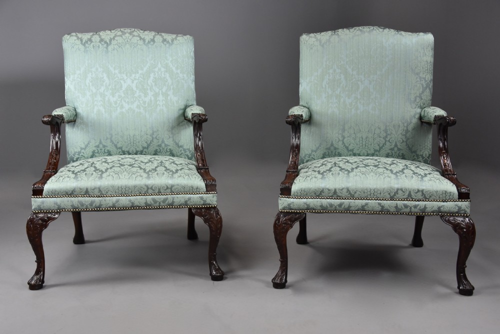 A pair of early 20th-century mahogany Gainsborough-style armchairs featuring carved cabriole legs with claw and ball feet, upholstered in light blue patterned damask fabric with brass stud trimming. View V