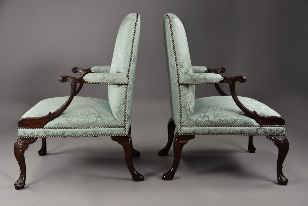 A pair of early 20th-century mahogany Gainsborough-style armchairs featuring carved cabriole legs with claw and ball feet, upholstered in light blue patterned damask fabric with brass stud trimming. View VIII