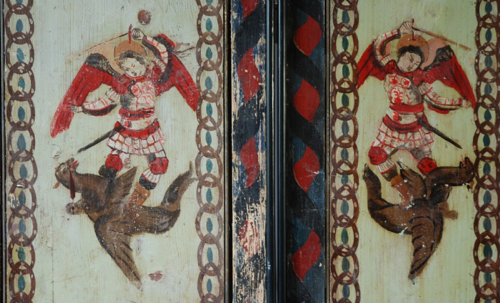 A set of four rectangular vertical pine panels decorated with naive paintings of Saint Michael slaying a winged dragon within chainlink borders. View II