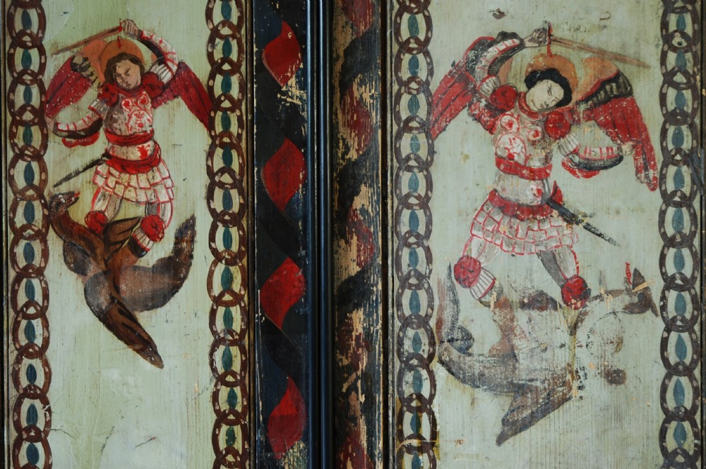 A set of four rectangular vertical pine panels decorated with naive paintings of Saint Michael slaying a winged dragon within chainlink borders. View III