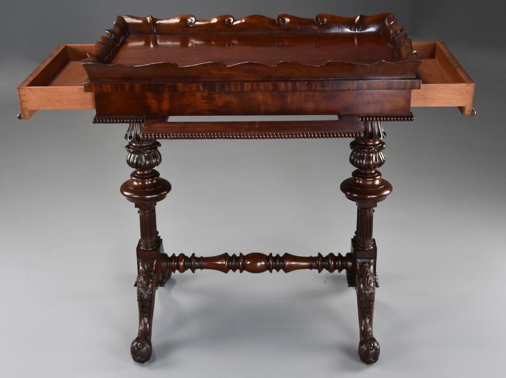 An early 19th century Regency mahogany work table featuring a wavy galleried tray top, flame mahogany apron with bead moulding, turned supports, and a carved stretcher base. View VIII