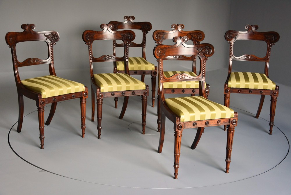 A set of six early nineteenth century Regency rosewood dining chairs with carved scroll crest rails and gold striped upholstered seats. View II