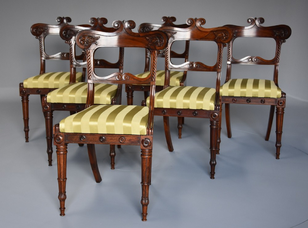 A set of six early nineteenth century Regency rosewood dining chairs with carved scroll crest rails and gold striped upholstered seats. View III