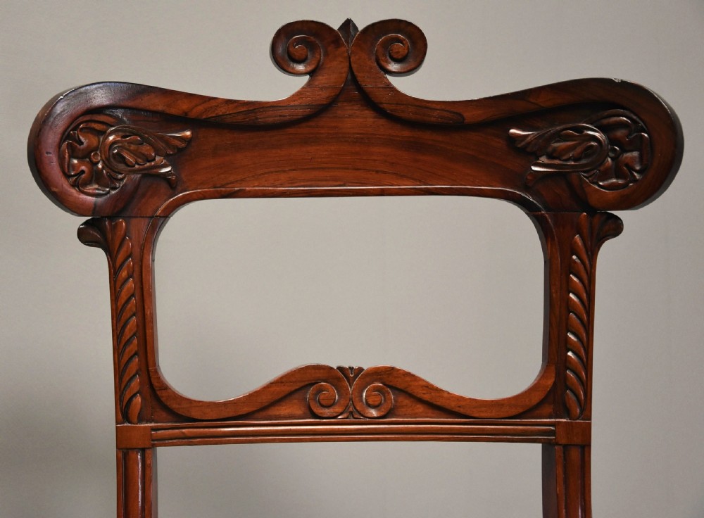 A set of six early nineteenth century Regency rosewood dining chairs with carved scroll crest rails and gold striped upholstered seats. View VI