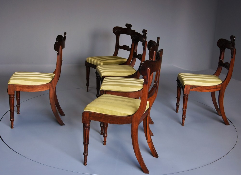 A set of six early nineteenth century Regency rosewood dining chairs with carved scroll crest rails and gold striped upholstered seats. View VII