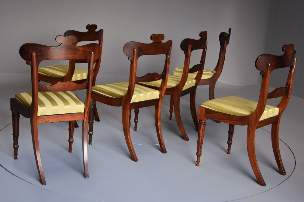A set of six early nineteenth century Regency rosewood dining chairs with carved scroll crest rails and gold striped upholstered seats. View VIII