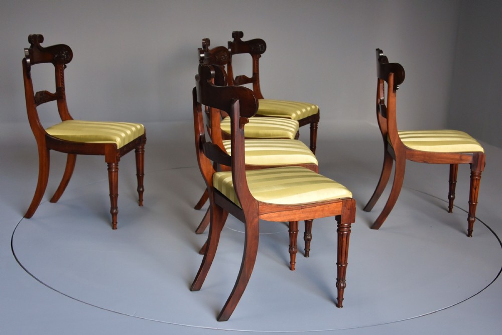 A set of six early nineteenth century Regency rosewood dining chairs with carved scroll crest rails and gold striped upholstered seats. View IX