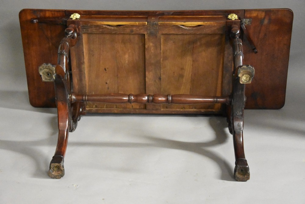 An early nineteenth-century French Empire mahogany sofa table featuring two drop leaves, a drawer with brass mounts, carved legs, and a turned central stretcher. View XII