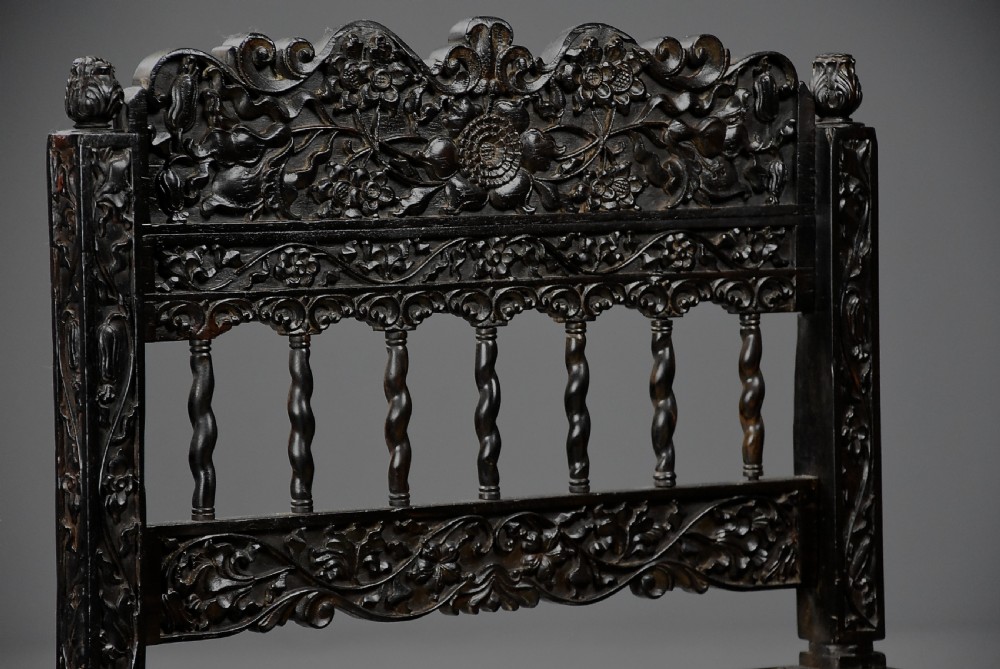 A 17th-century dark carved ebony low chair featuring floral relief carving on the frame, a hand-woven cane seat, and spiralled barley-twist legs. View VIII