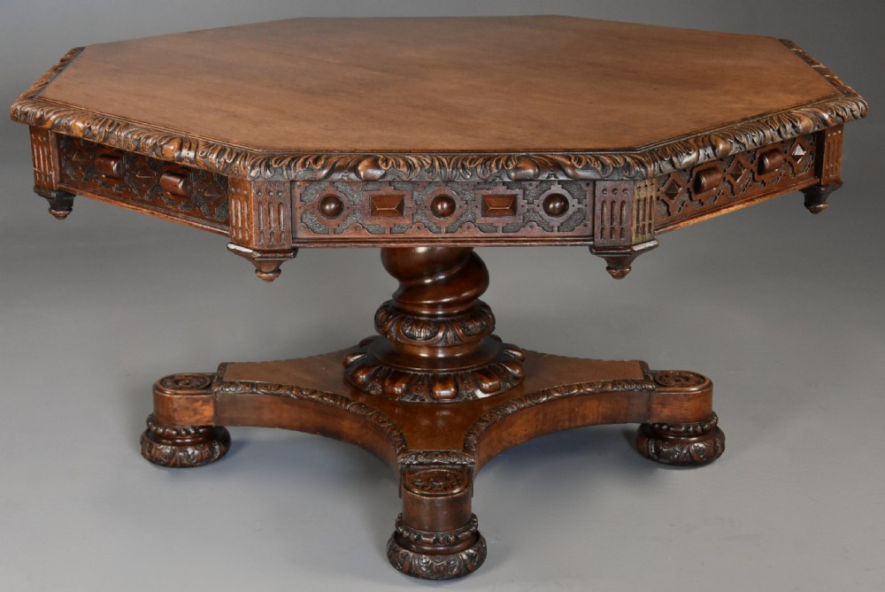 An early 19th-century octagonal carved oak library table with a central spiral pedestal and geometric strapwork frieze.