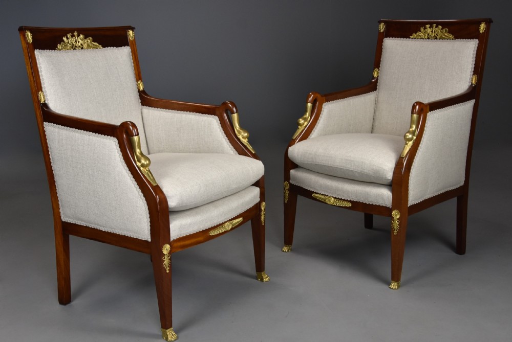 A pair of early 20th-century French Empire style mahogany armchairs featuring light neutral upholstery and gilt bronze mounts. View II