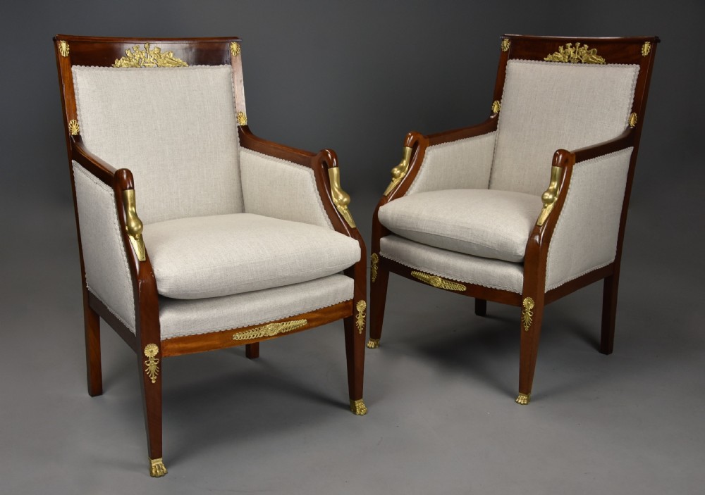 A pair of early 20th-century French Empire style mahogany armchairs featuring light neutral upholstery and gilt bronze mounts. View IV