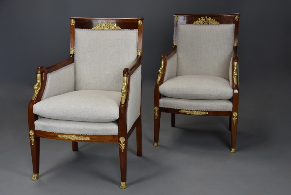 A pair of early 20th-century French Empire style mahogany armchairs featuring light neutral upholstery and gilt bronze mounts. View VI