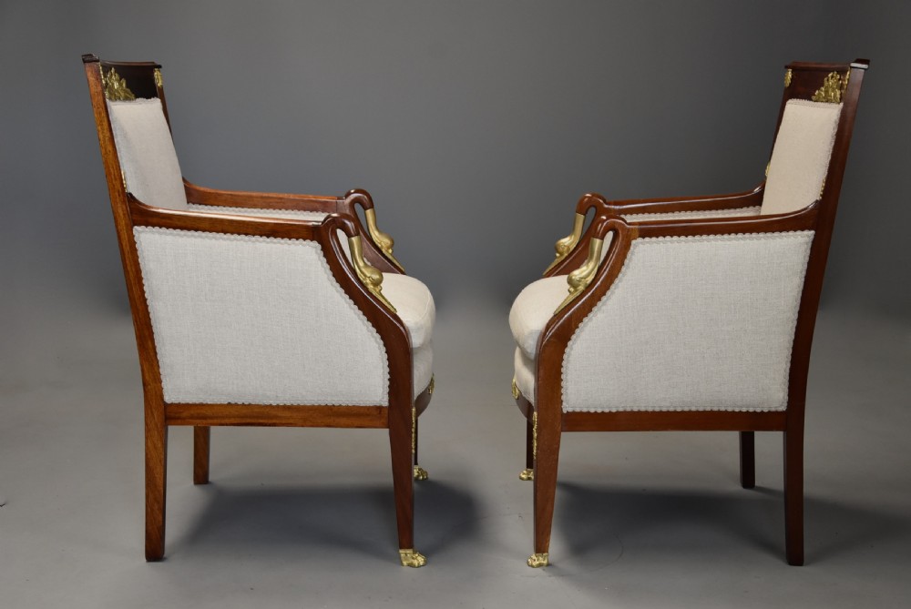A pair of early 20th-century French Empire style mahogany armchairs featuring light neutral upholstery and gilt bronze mounts. View VIII